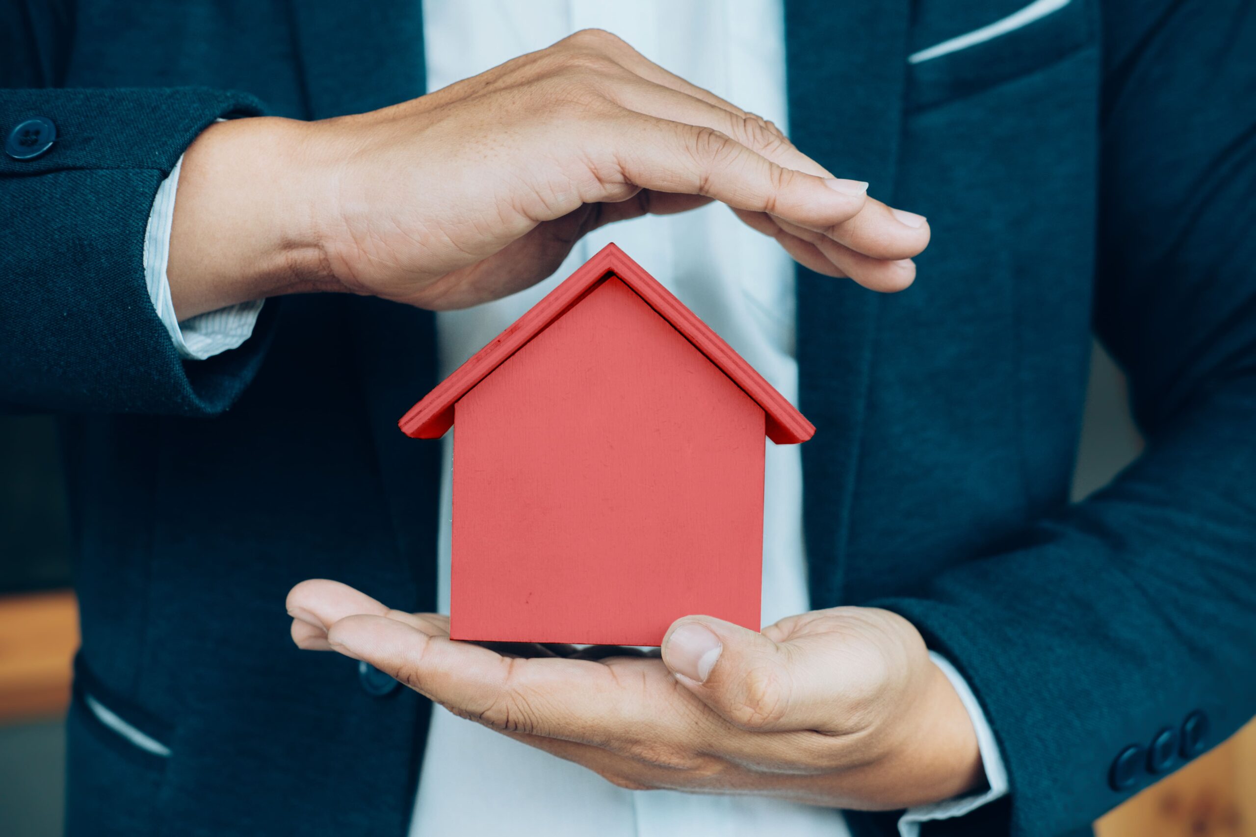 business man hand hold house model saving small house