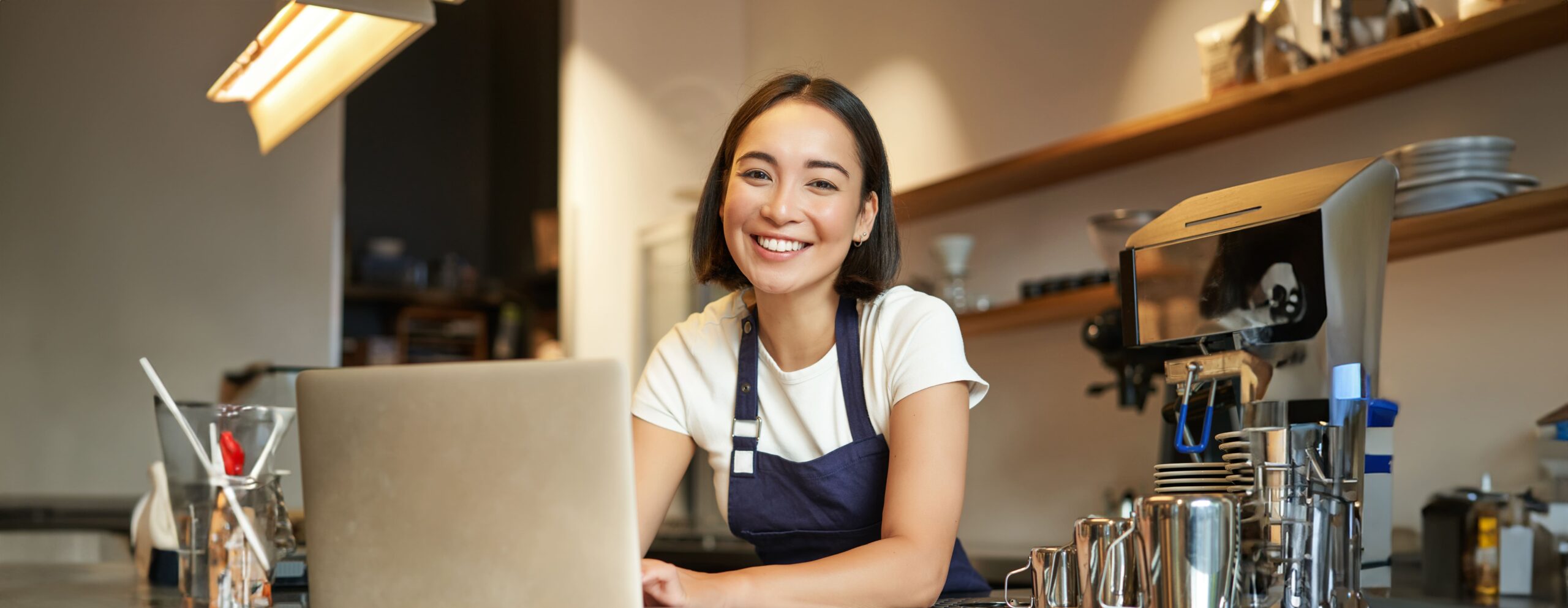 enthusiastic asian girl cafe uniform barista worker with laptop looking happy surprised (2)