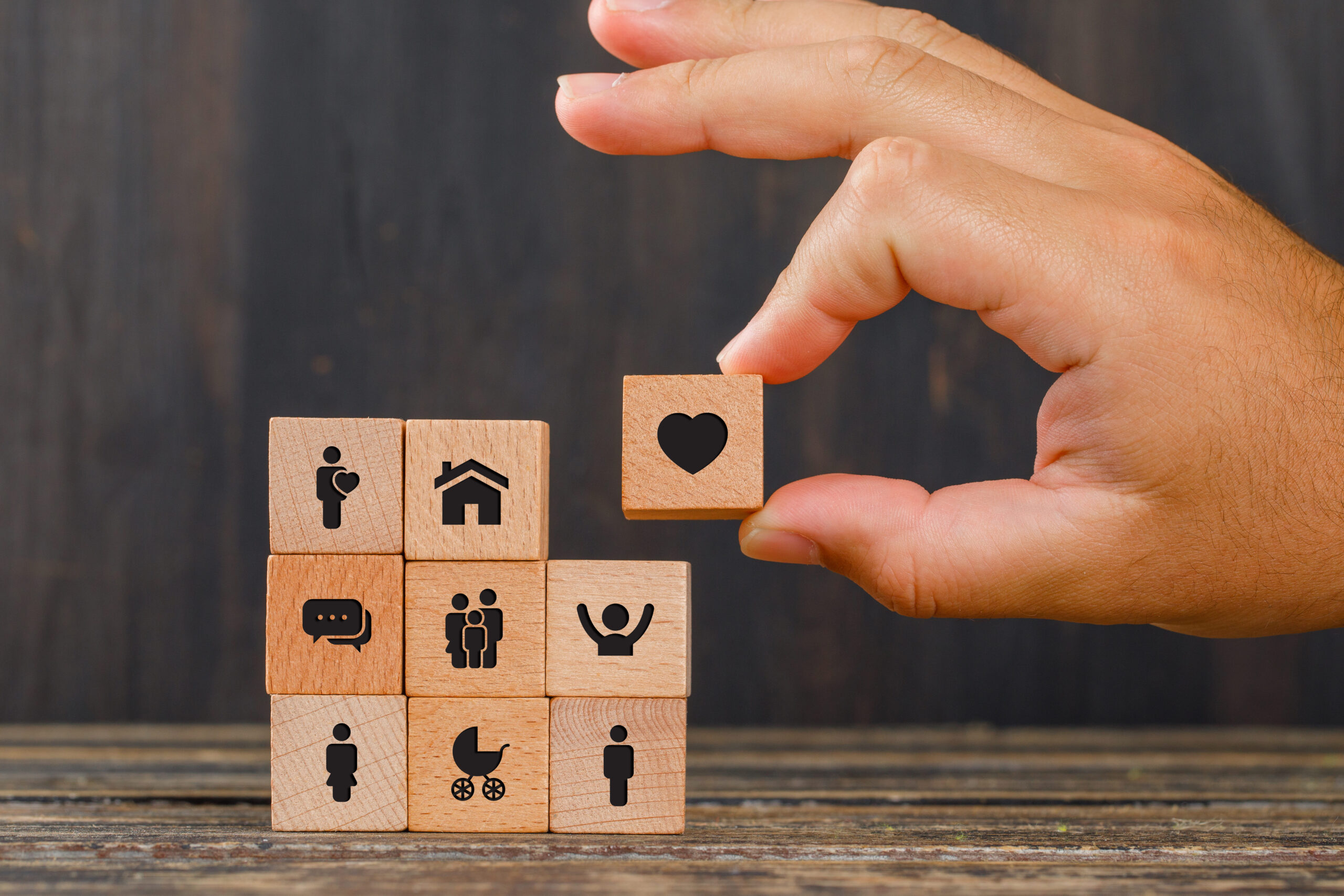 relationship concept wooden table side view hand holding wooden cube with heart icon (2)